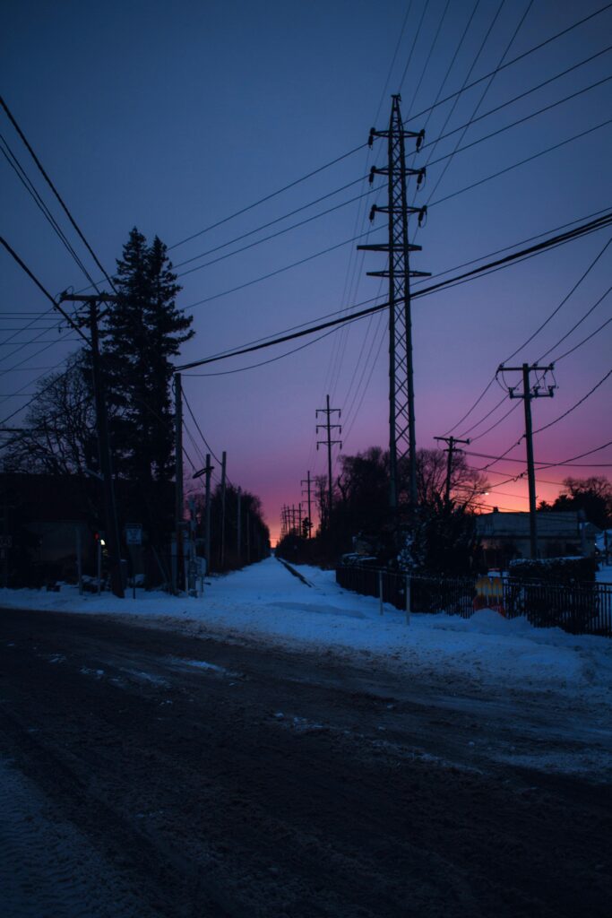 Snowy street with power lines at sunset, creating a moody winter scene.
